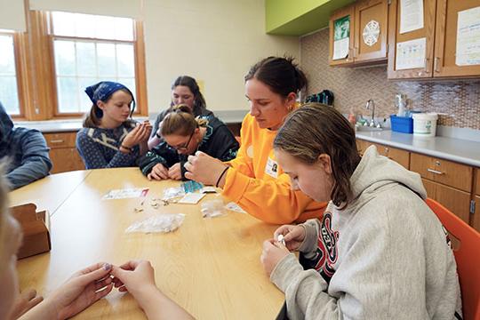 Abigail Gatza helping students assemble robots