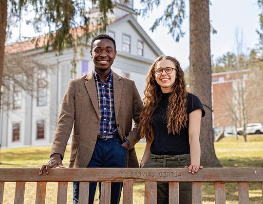 photo of two 学生 standing behind a park bench