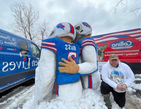 man kneeling next to snow sculpture