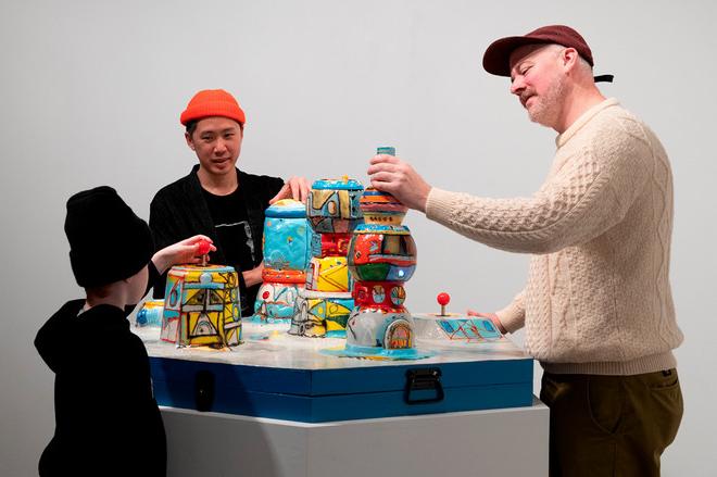 three people playing and interacting with colorful station of pots