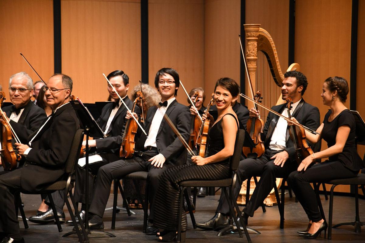 orchestra members back stage smiling for the camera